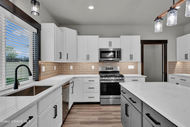 2878 N Callary St, Post Falls, ID 83854 - kitchen with light wood-style flooring, a sink, tasteful backsplash, appliances with stainless steel finishes, and light stone counters
