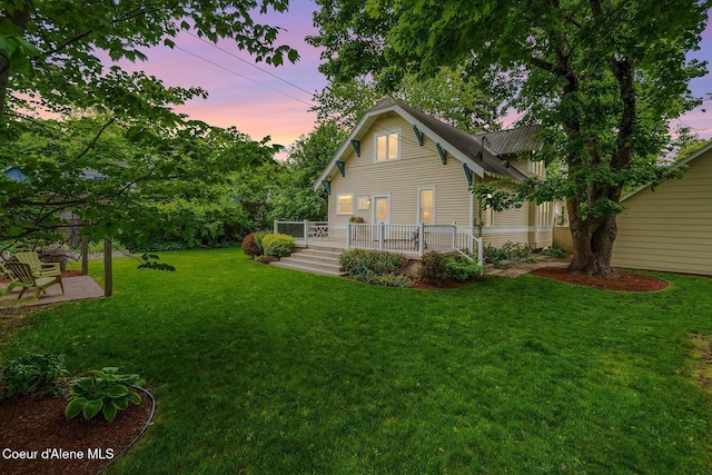 306 S Huron Ave, Sandpoint, ID 83864 - back of property at dusk with a yard, a wooden deck, and a patio area