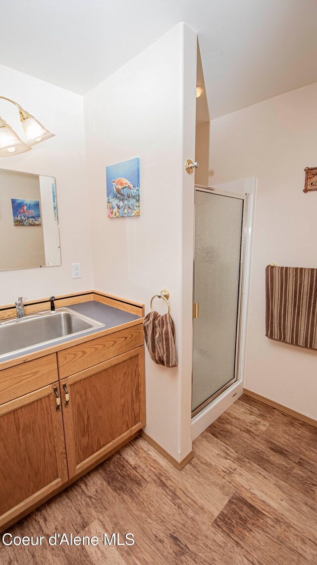 6616 Comanche St, Bonners Ferry, ID 83805 - bathroom featuring vanity, baseboards, wood finished floors, and a stall shower