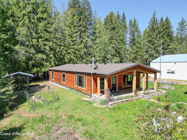 rear view of house with a lawn, metal roof, and a patio