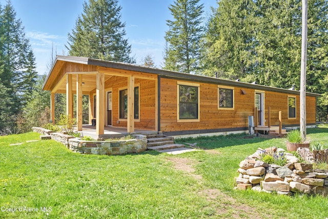 back of property featuring covered porch and a yard