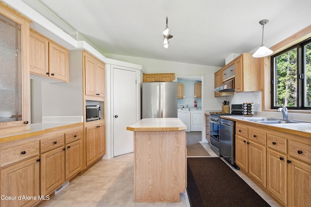 kitchen featuring a center island, a sink, washing machine and clothes dryer, under cabinet range hood, and appliances with stainless steel finishes