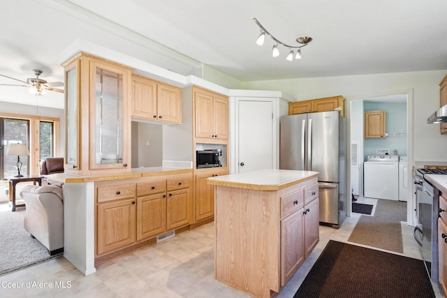 kitchen with stainless steel appliances, washer and dryer, ceiling fan, light countertops, and a kitchen island