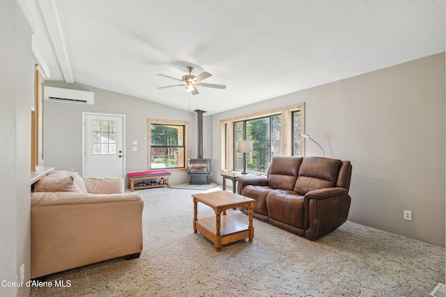 living room featuring lofted ceiling with beams, a wood stove, an AC wall unit, carpet flooring, and a ceiling fan