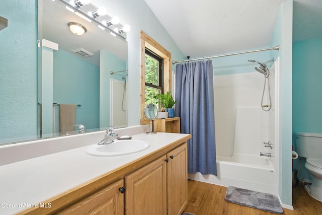 bathroom featuring toilet, wood finished floors, vanity, visible vents, and shower / tub combo