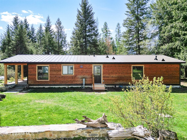 back of property with a yard and metal roof
