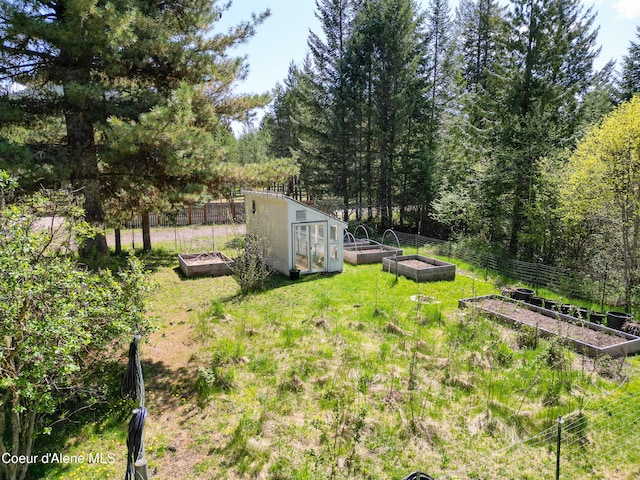view of yard with a storage unit, fence, a garden, and an outbuilding