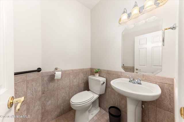 12795 N Yearling Cir, Hayden, ID 83835 - bathroom featuring toilet, tile walls, tile patterned flooring, and a wainscoted wall