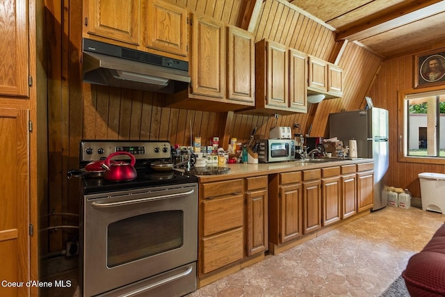 760 Fox Glen Rd, Sandpoint, ID 83864 - kitchen featuring under cabinet range hood, brown cabinetry, wood walls, light countertops, and appliances with stainless steel finishes