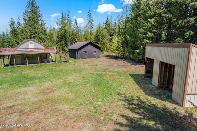 760 Fox Glen Rd, Sandpoint, ID 83864 - view of yard featuring an outbuilding, a wooded view, a pole building, stairs, and a wooden deck