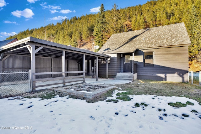 513 Mission Ave, Kellogg, ID 83837 - snow covered rear of property featuring a wooded view and roof with shingles