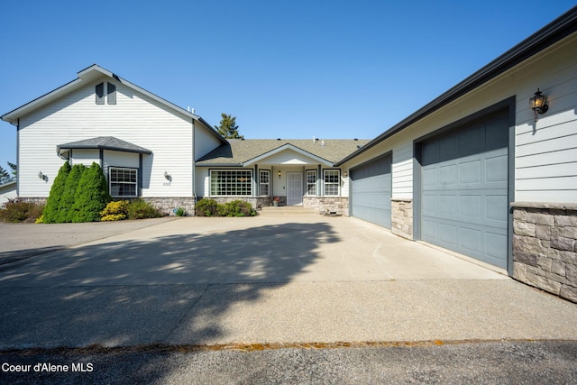 view of front of house with driveway, stone siding, an attached garage, and roof with shingles