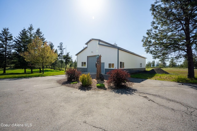 view of home's exterior featuring a yard, a detached garage, asphalt driveway, and an outdoor structure