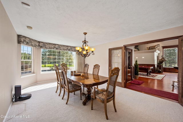 dining room featuring carpet flooring, plenty of natural light, a textured ceiling, and a chandelier