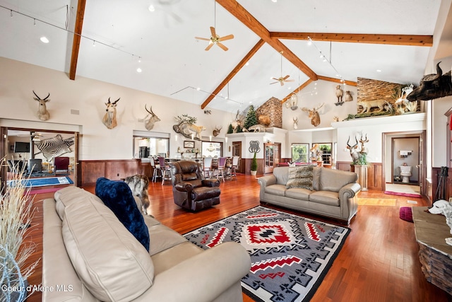 living room with high vaulted ceiling, beam ceiling, wood finished floors, a ceiling fan, and wainscoting
