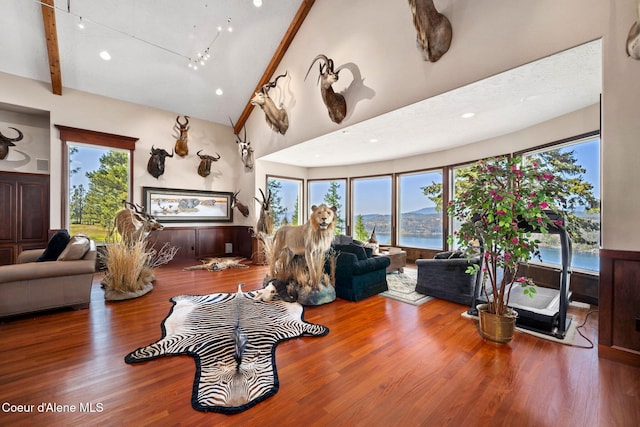 living room with wood finished floors, high vaulted ceiling, beam ceiling, and a water view