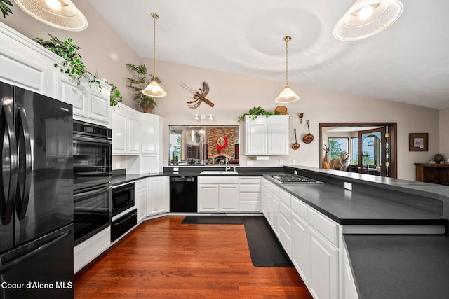 kitchen featuring black appliances, dark countertops, vaulted ceiling, a peninsula, and dark wood-type flooring