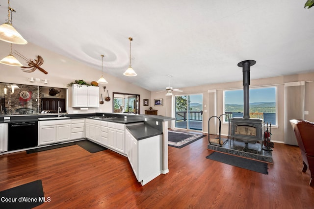 kitchen with dishwasher, dark countertops, a wood stove, a peninsula, and open floor plan