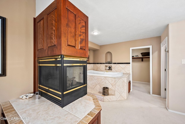 bathroom with a bath, baseboards, and a multi sided fireplace