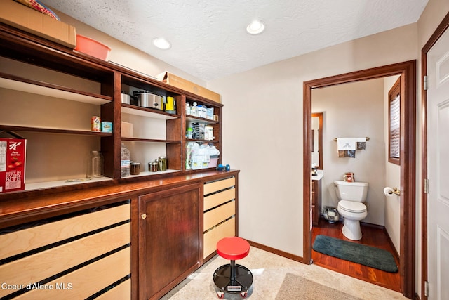 office area featuring a textured ceiling, baseboards, recessed lighting, and a bar