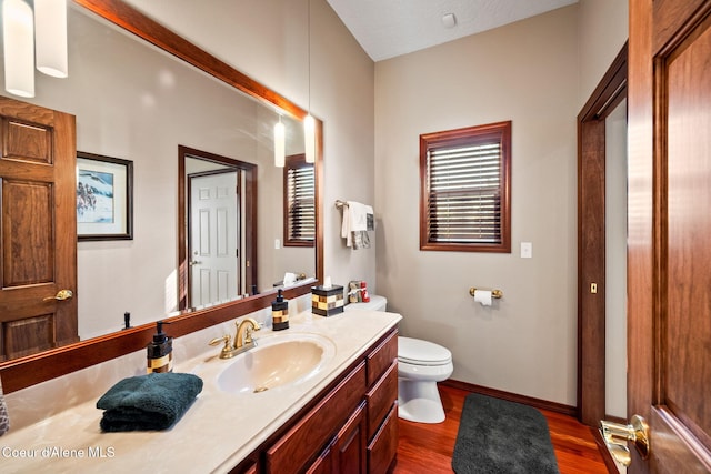 bathroom with wood finished floors, toilet, vanity, and baseboards