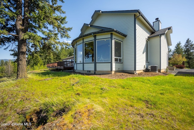 back of property with a deck, a yard, central air condition unit, and a chimney