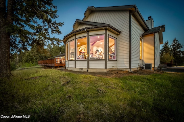 rear view of property featuring central AC unit, a deck, and a chimney