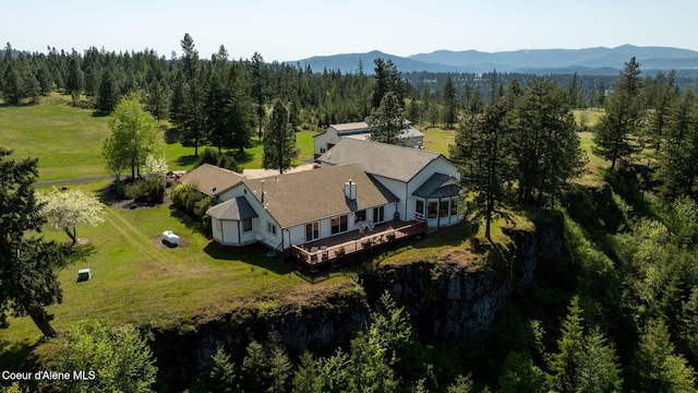 aerial view of property and surrounding area featuring a forest and a mountain backdrop