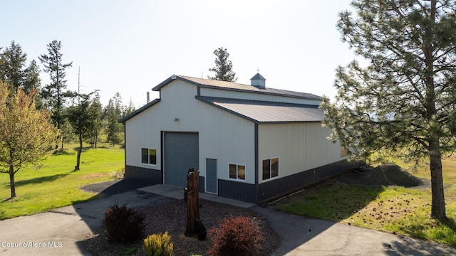 view of home's exterior with a garage, a lawn, metal roof, and driveway