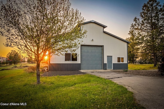 view of home's exterior featuring driveway, a lawn, a garage, and an outbuilding