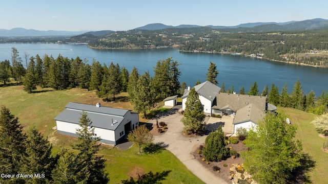 view of subject property featuring a water and mountain view and a heavily wooded area