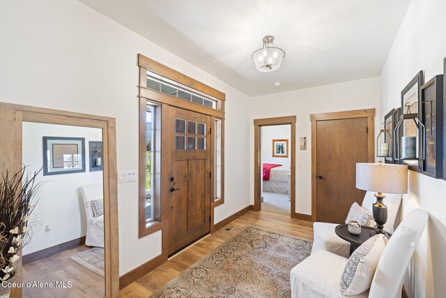 entryway featuring a chandelier, light wood-style floors, and baseboards