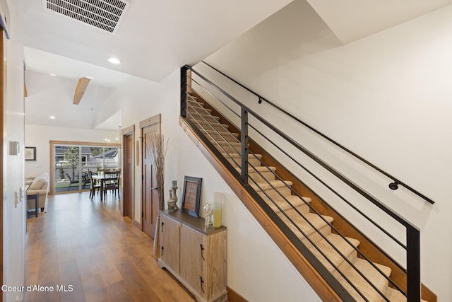 stairway featuring wood finished floors, recessed lighting, and lofted ceiling