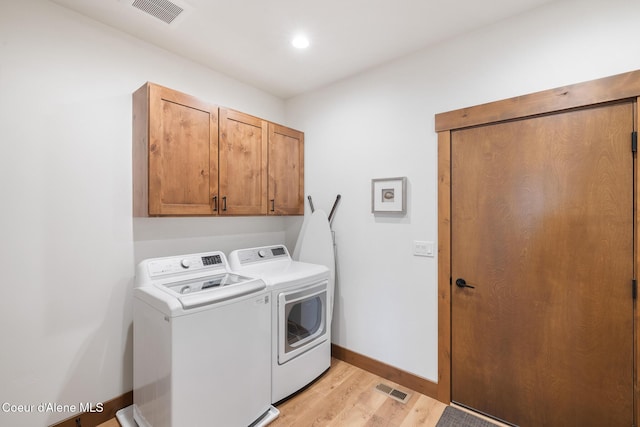 washroom featuring washing machine and dryer, cabinet space, light wood finished floors, and baseboards