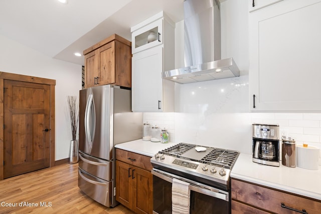kitchen with appliances with stainless steel finishes, wall chimney exhaust hood, light countertops, decorative backsplash, and recessed lighting