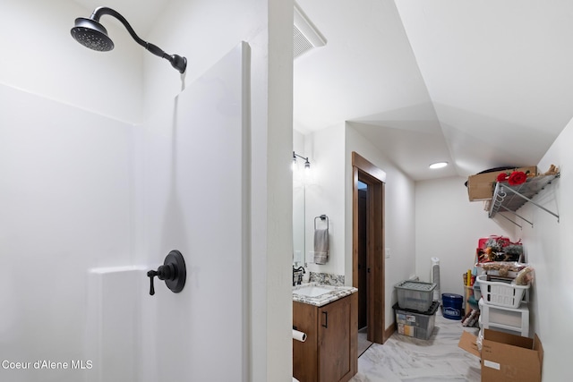 bathroom featuring a shower, marble look tiles, and vanity