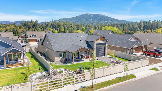 view of front of property featuring driveway, an attached garage, a residential view, a mountain view, and a shingled roof