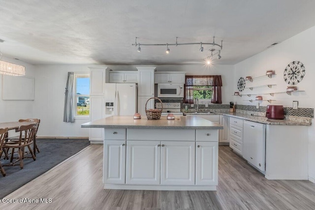 9727 W E St, Worley, ID 83876 - kitchen with white appliances, white cabinetry, light wood-type flooring, and a center island