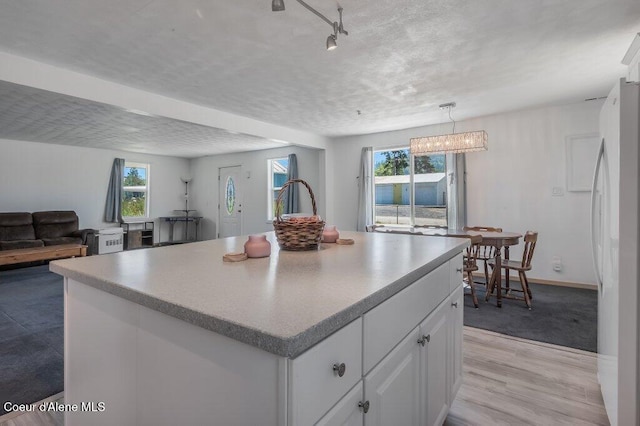 9727 W E St, Worley, ID 83876 - kitchen featuring freestanding refrigerator, white cabinetry, light wood-type flooring, plenty of natural light, and a textured ceiling