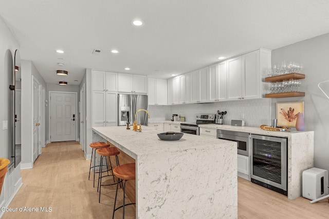 4797 S Arrow Point Dr # 102, Harrison, ID 83833 - kitchen featuring wine cooler, stainless steel appliances, white cabinetry, and light wood-type flooring