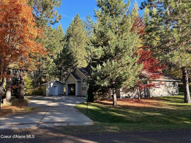 view of front of property featuring an outdoor structure, driveway, a front yard, and a storage unit