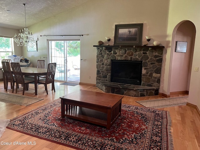 living room with lofted ceiling, wood finished floors, a textured ceiling, arched walkways, and baseboards