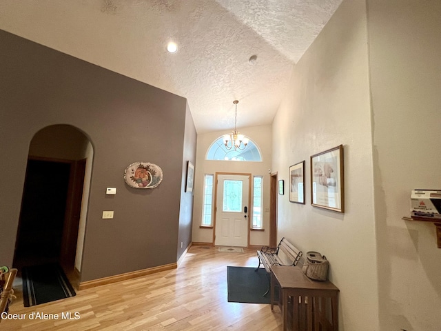 927 Bear Claw Rd, Clark Fork, ID 83811 - entryway featuring a textured ceiling, light wood-style flooring, arched walkways, a chandelier, and baseboards