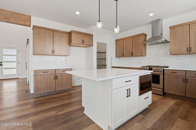 6760 Portrush Dr, Rathdrum, ID 83858 - kitchen with wall chimney range hood, backsplash, light countertops, dark wood-style floors, and appliances with stainless steel finishes