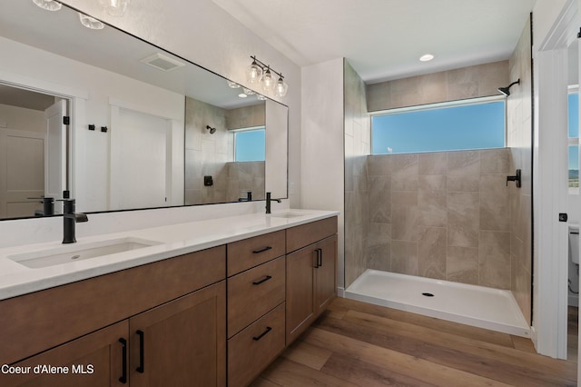 6760 Portrush Dr, Rathdrum, ID 83858 - full bathroom with tiled shower, double vanity, a sink, and wood finished floors