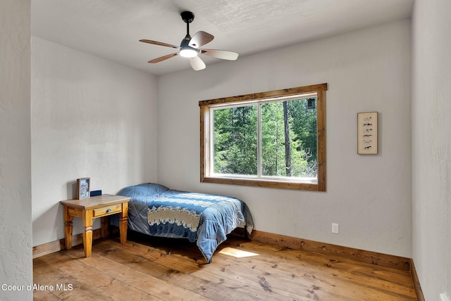 bedroom with baseboards, a ceiling fan, and hardwood / wood-style flooring
