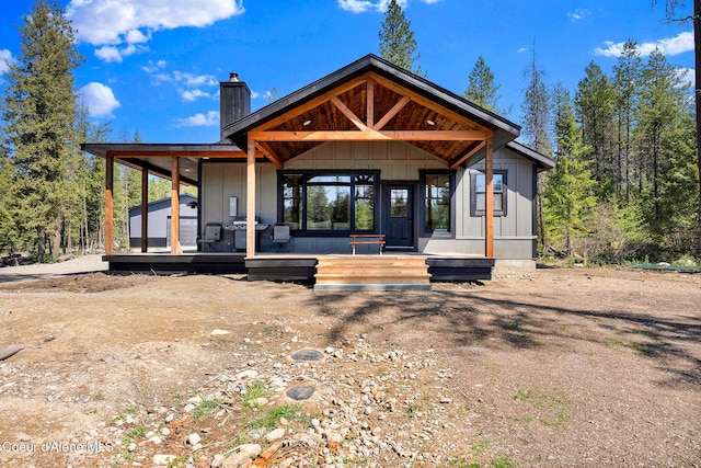 rear view of property featuring covered porch and a chimney