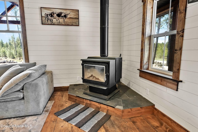 room details featuring baseboards, a wood stove, wood walls, and wood finished floors