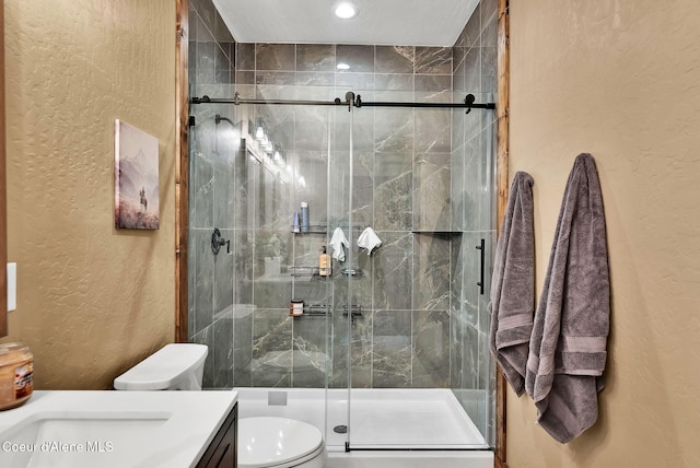 full bathroom featuring a stall shower, recessed lighting, toilet, vanity, and a textured wall