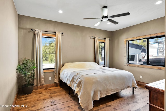 bedroom featuring baseboards, multiple windows, and hardwood / wood-style flooring